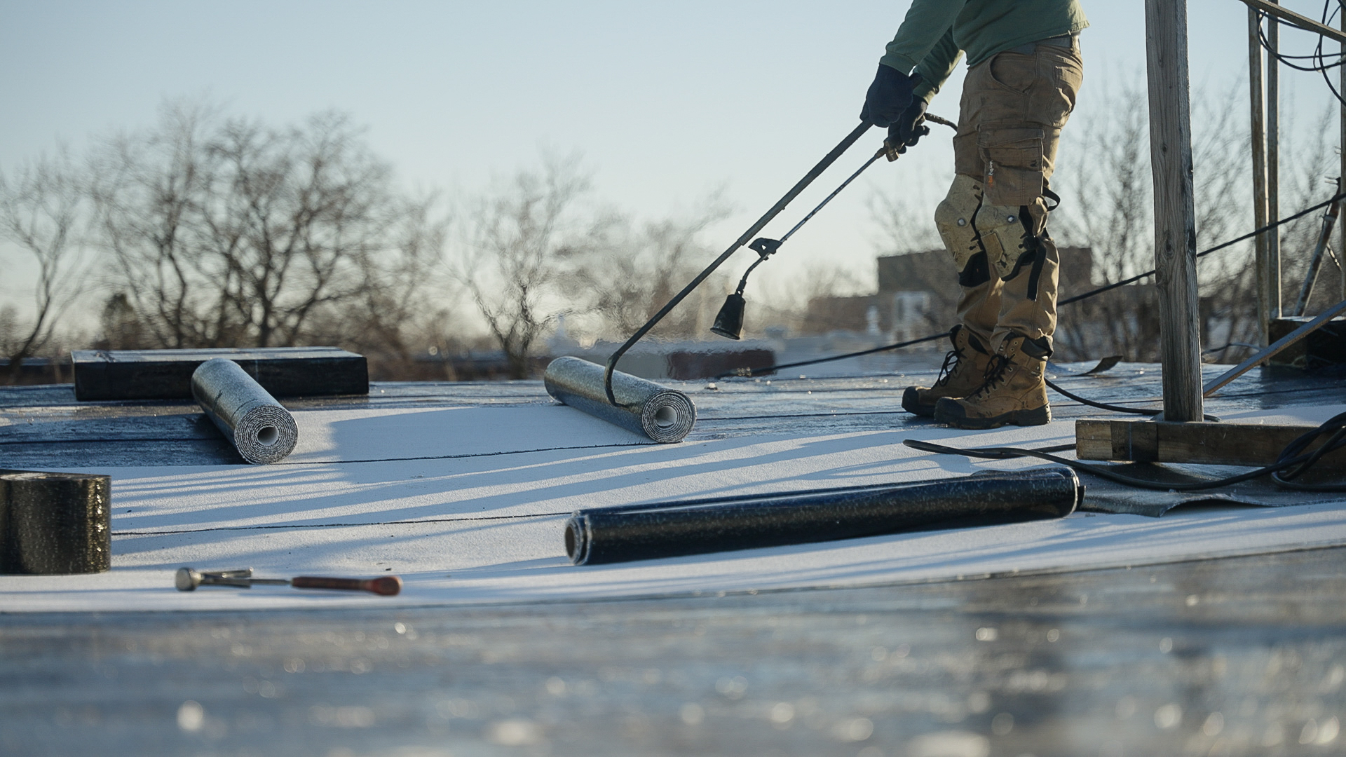 Couvreur Toitex inspectant une toiture avec chalumeau sur toit plat